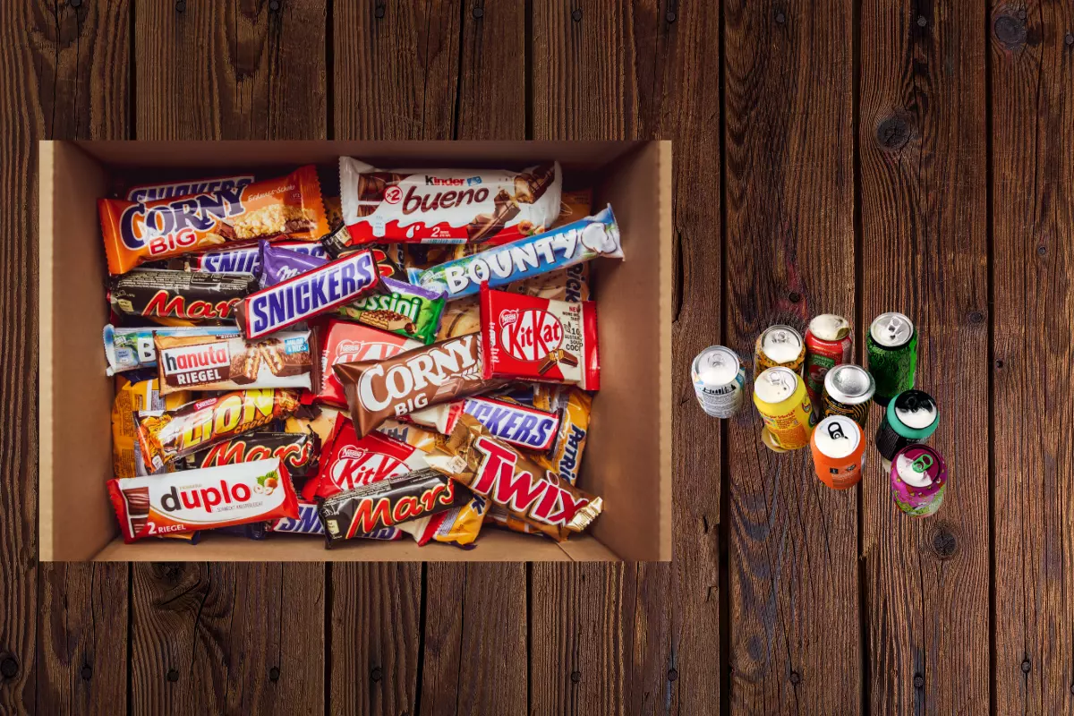 a box of snacks and can bottles of beverages on wooden floor