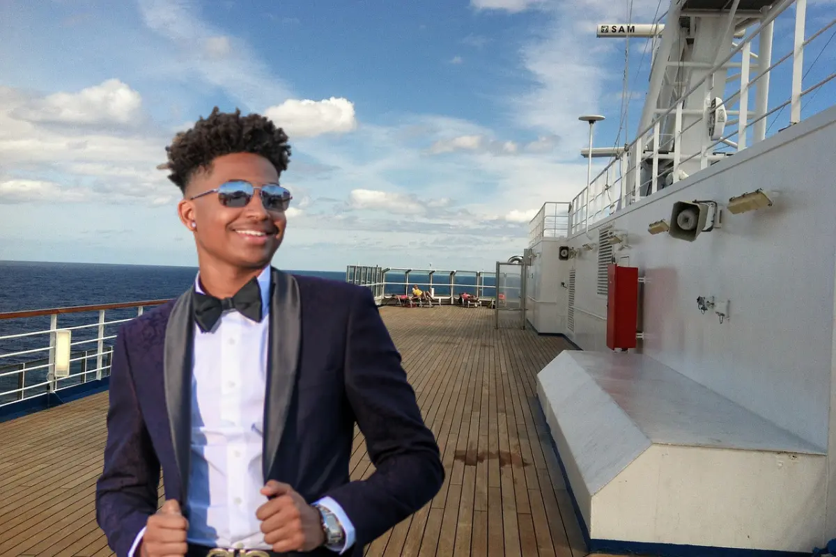 man standing on the deck of a cruise ship wearing a tuxedo.