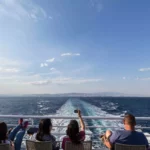 Tourists sitting with their mobile phones on a cruise ship.