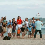 a large family in front of a cruise ship posing for a photo.